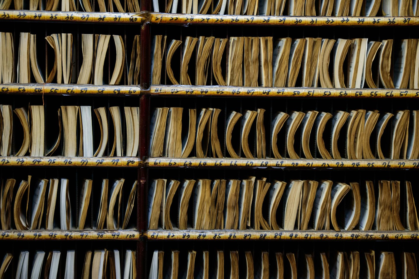 Reihen von hölzernen Fächern enthalten ordentlich gestapelte Archivdokumente.