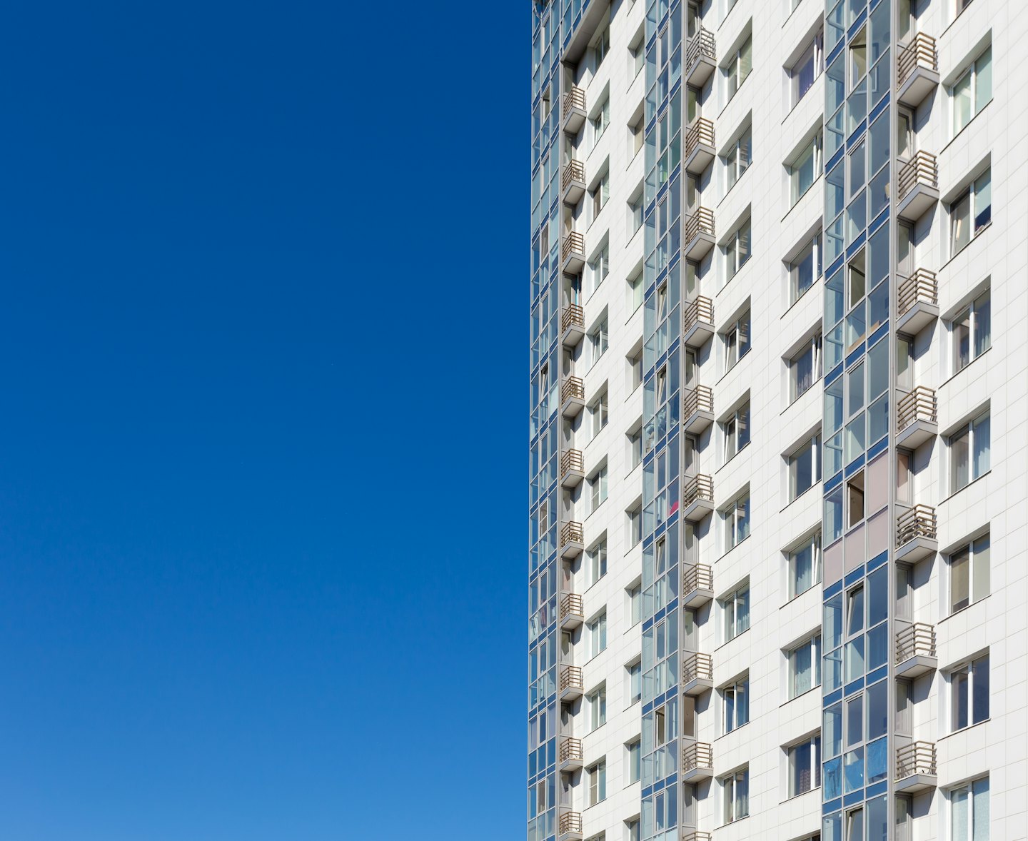 Modernes weiß gefliestes Gebäude mit blauen Glasfenstern.